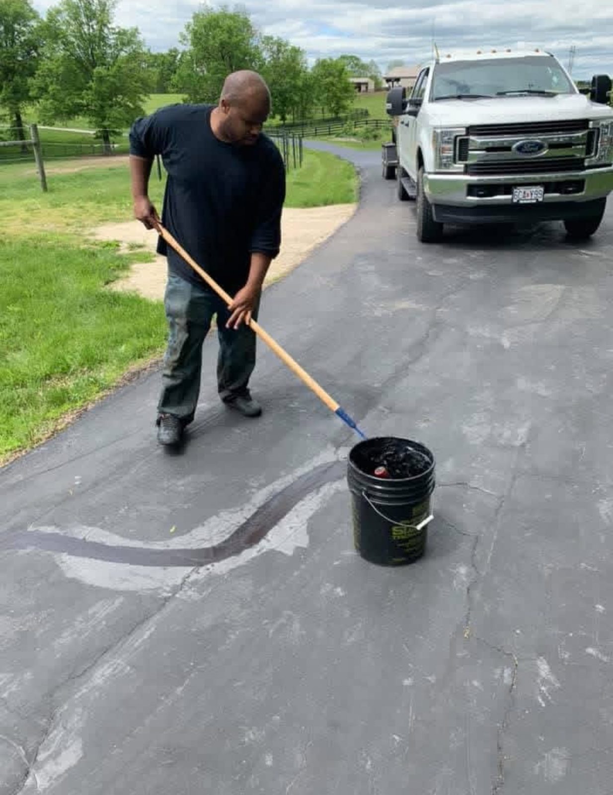 Crew member applying sealer to a driveway by hand