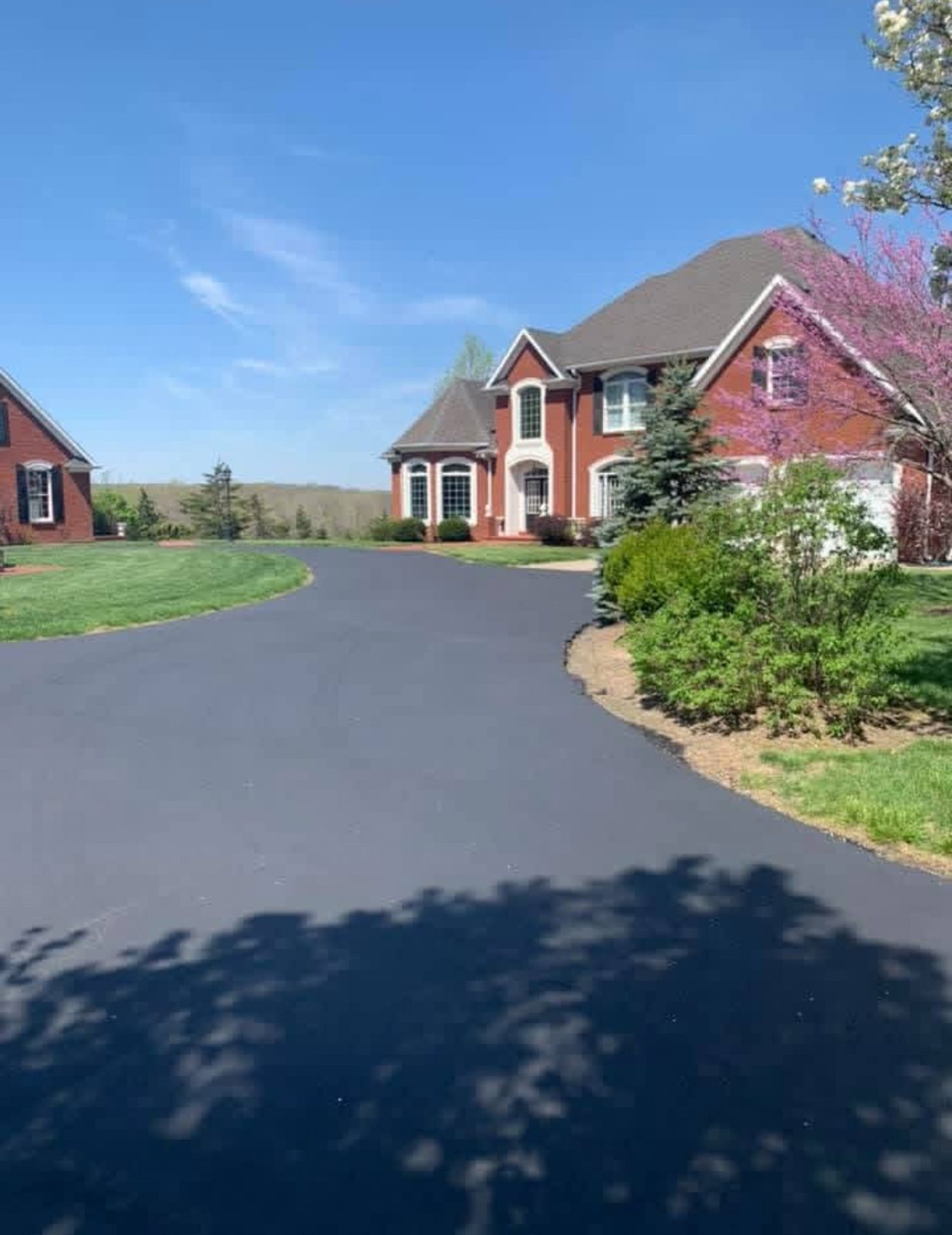 Wide residential driveway after sealcoating, finished deep black