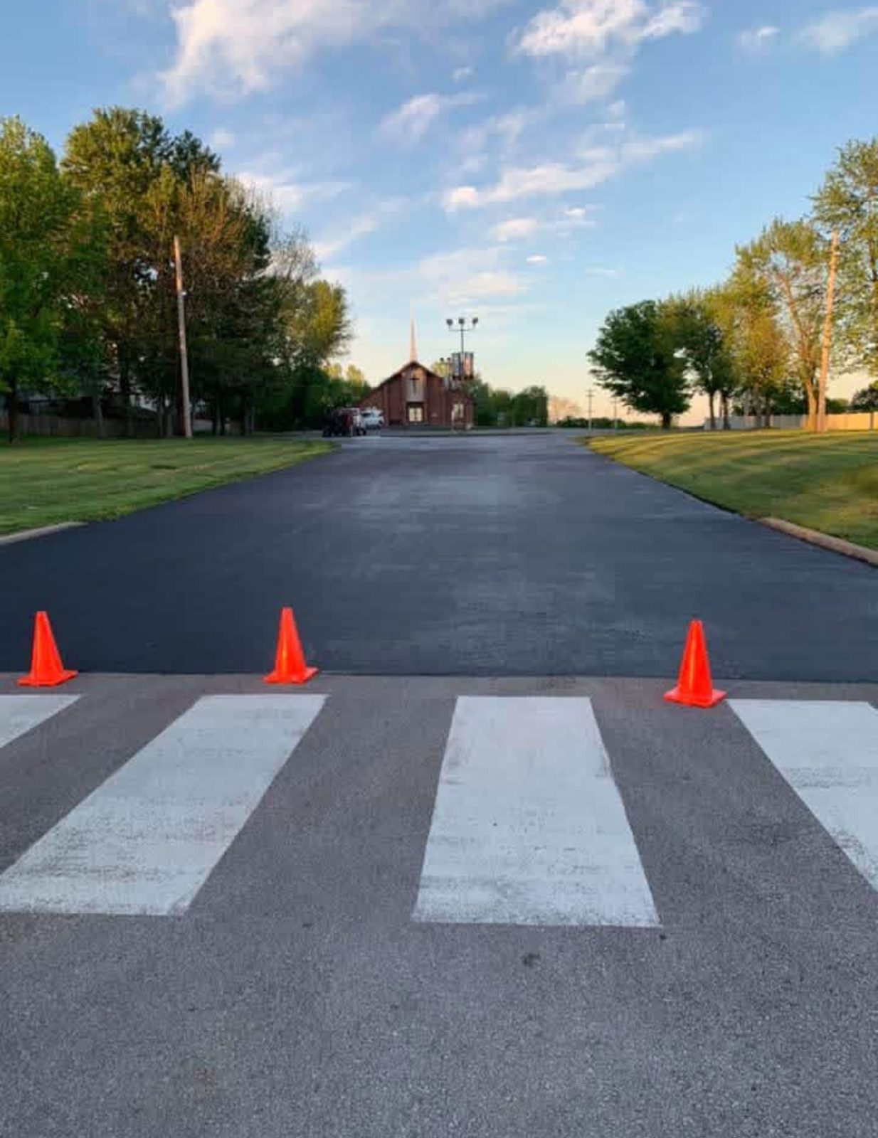 Fresh white crosswalk bars painted across new asphalt